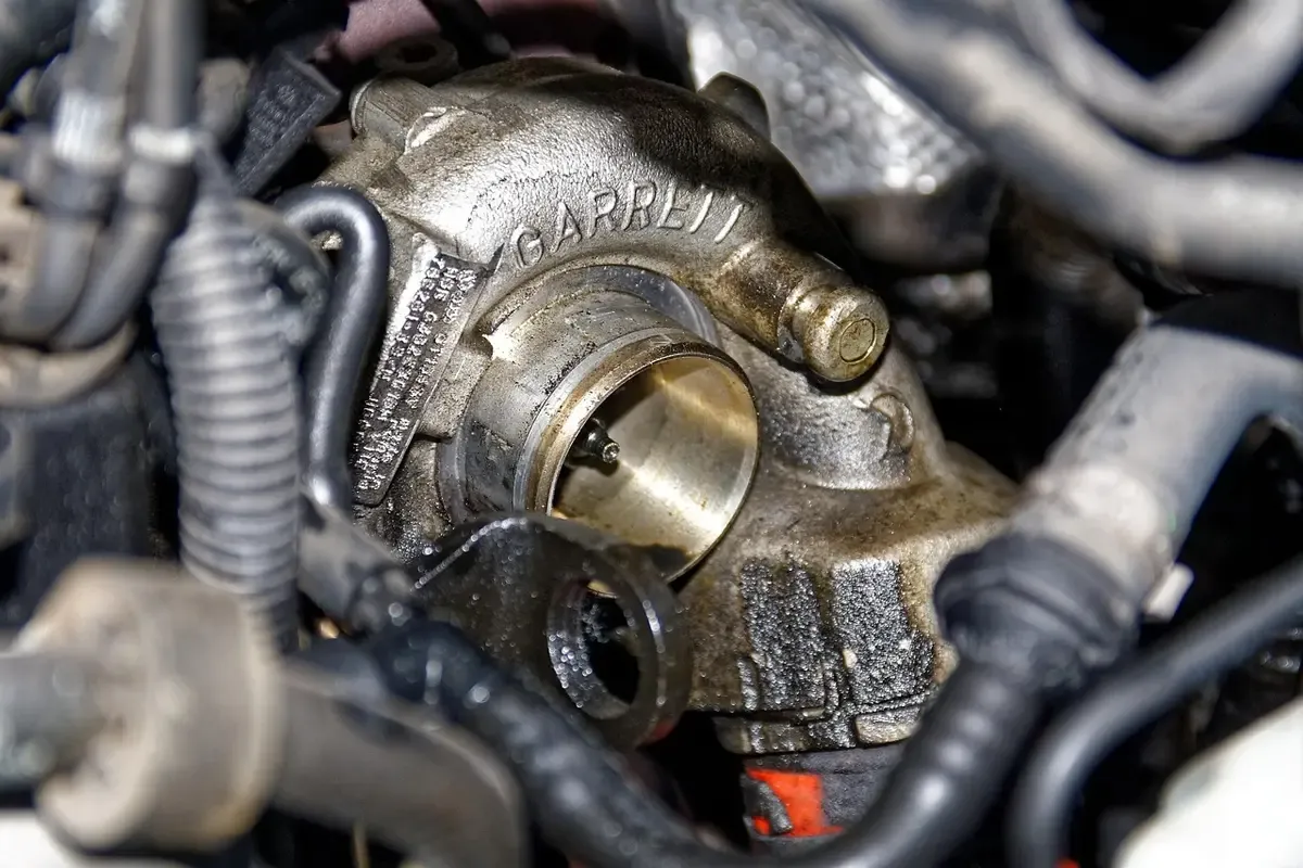 Turboaggregat monterat i ett oljigt motorrum med sotiga ytor